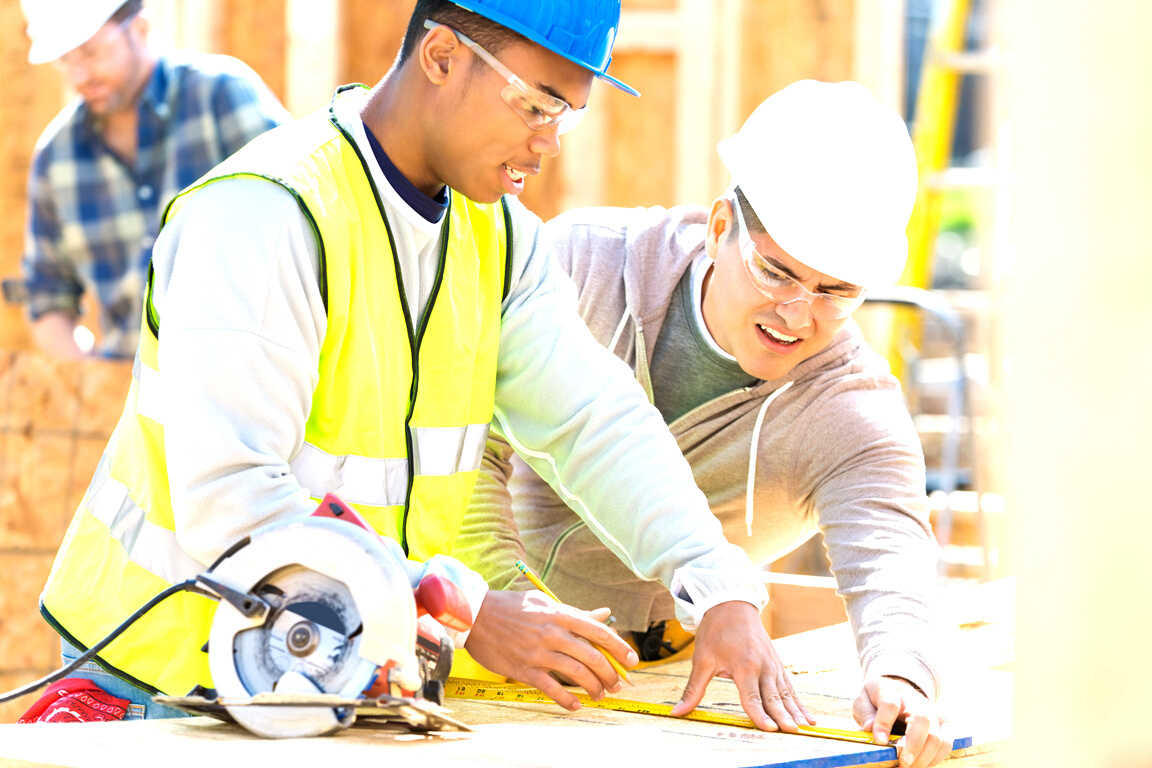 Construction workers measure board at job site